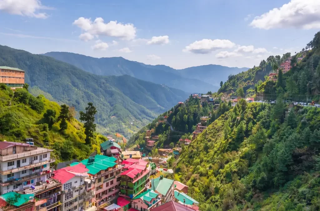Scenic view of Shimla hill station with colorful houses, lush green mountains, and panoramic Himalayan landscape under a clear blue sky