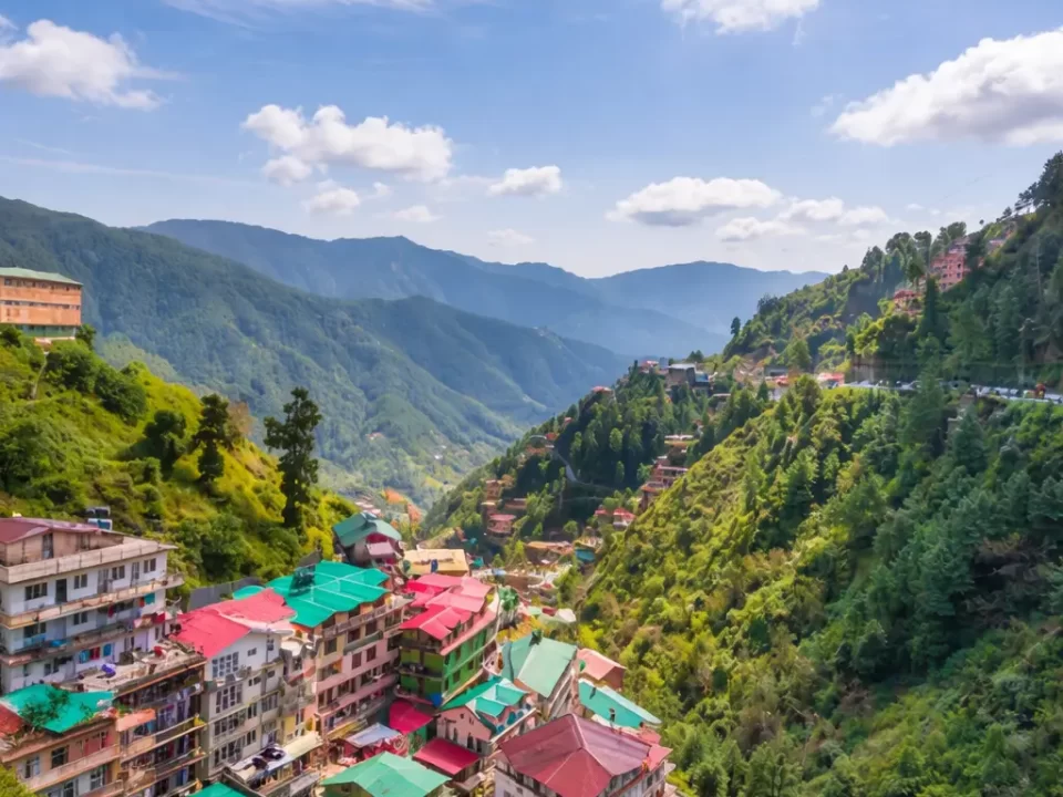 Scenic view of Shimla hill station with colorful houses, lush green mountains, and panoramic Himalayan landscape under a clear blue sky